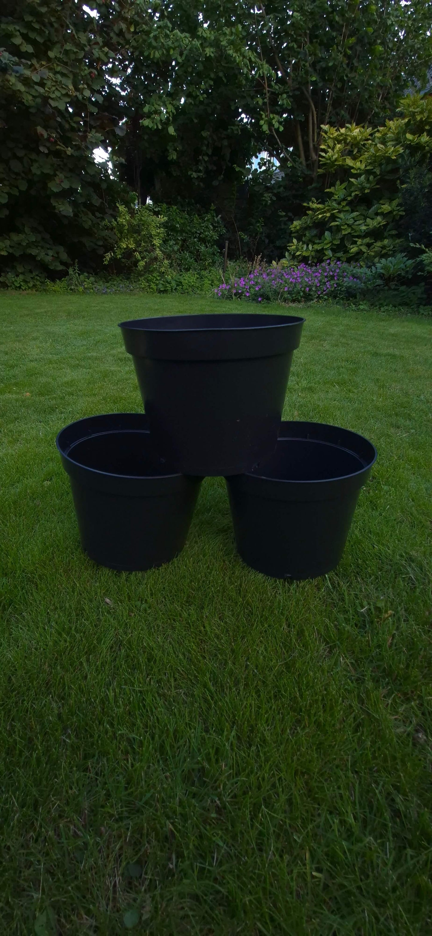 Drie plantenpotten zwart op gras